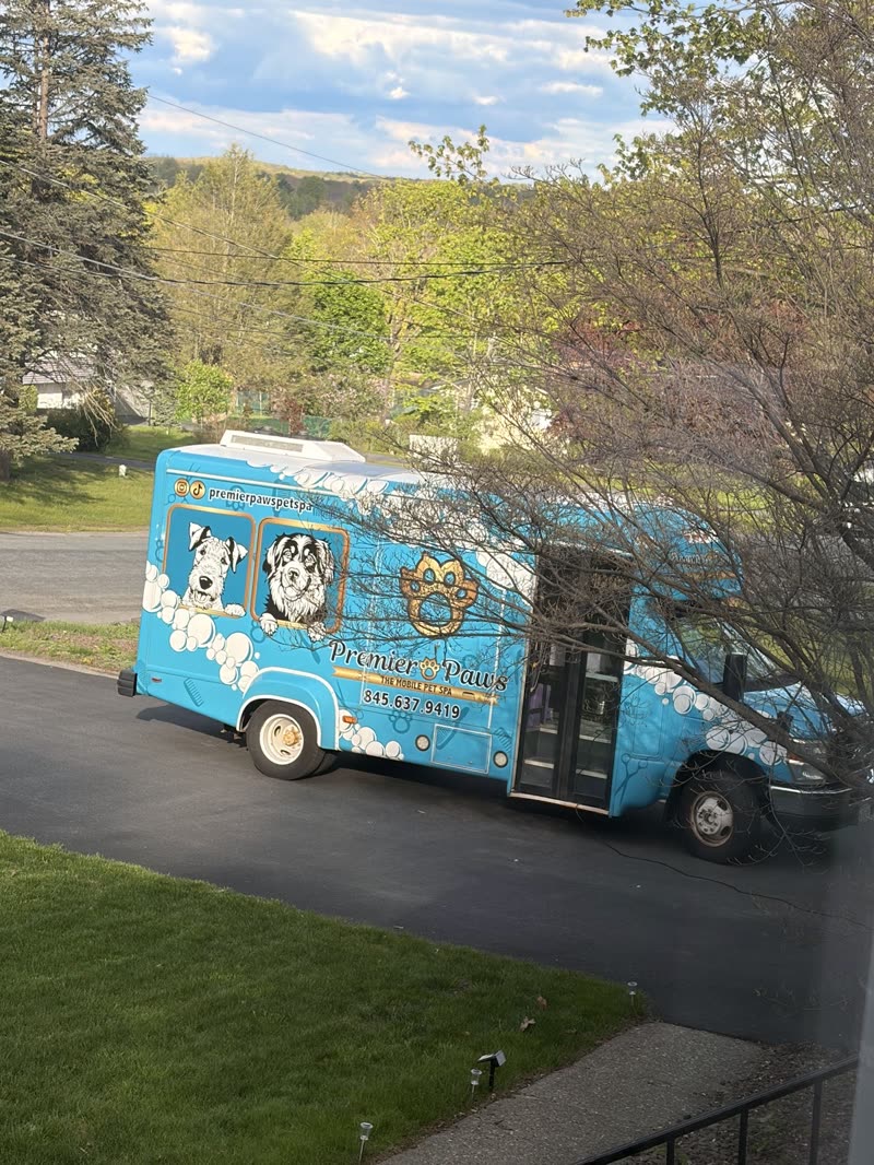 The grooming van on a driveway with its side door open, lawn and sky behind